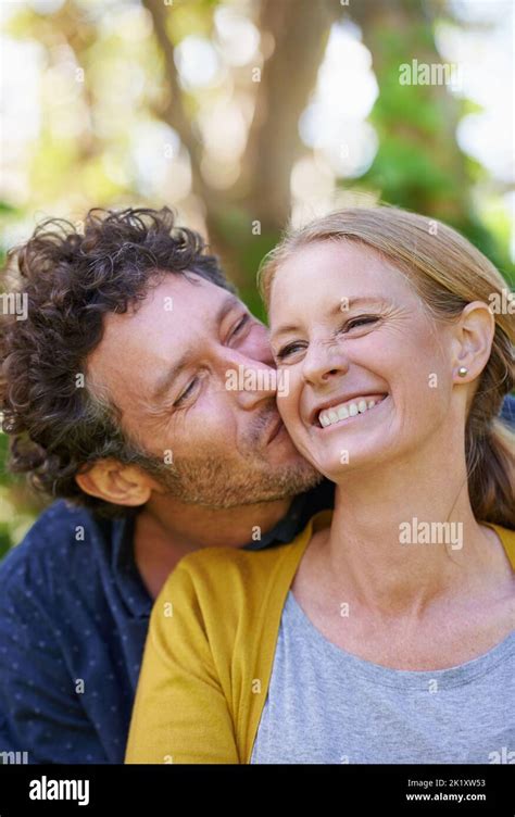 Giving Her A Big Kiss On The Cheek An Affectionate Husband And Wife Standing Outdoors Stock