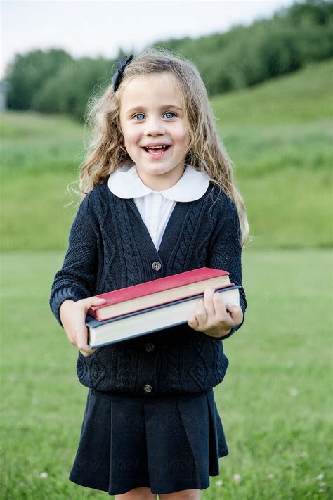 Portrait Of School Girl Standing In A Field With Two Books Del Colaborador De Stocksy Shaun