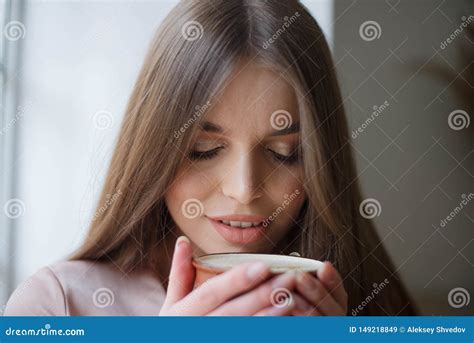 Beautiful Girl Is Drinking Coffee And Smiling While Sitting At The Cafe