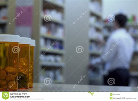 Pill Bottles On A Pharmacy Counter With Pharmacist In Background Stock