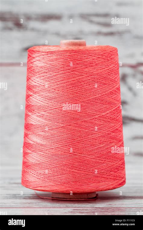 Spool Of Synthetic Pink Thread On White Wooden Background Stock Photo