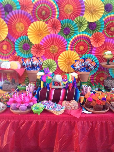 A Table Topped With Lots Of Desserts And Colorful Paper Umbrellas Behind The Table