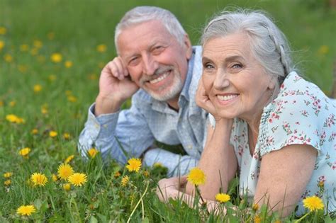 Premium Photo Happy Senior Couple Lying On Green Meadow With Dandelions