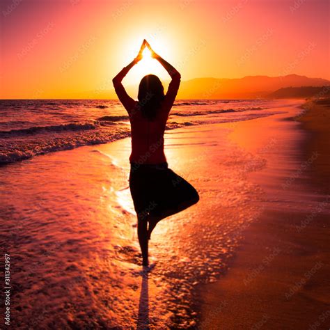 Zdjęcie Stock Girl Silhouette In Yoga Vrksasana Tree Pose Balancing On One Leg In Ocean Catches
