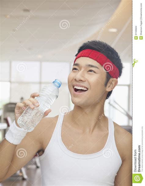 Portrait Of Smiling Young Man Drinking From Water Bottle