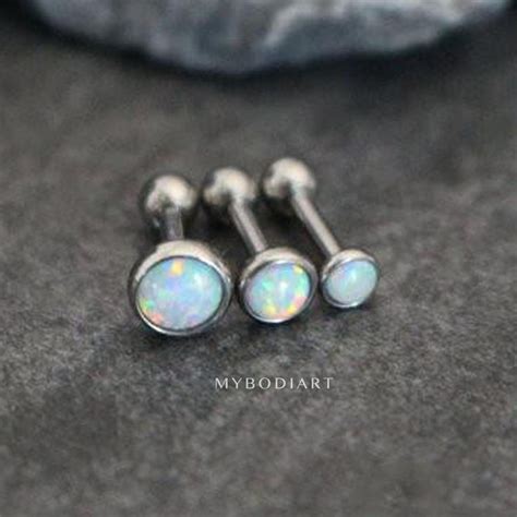 Three White Opal Piercings Are Sitting On A Black Surface