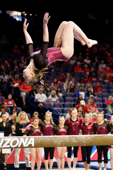 University Of Denver Gymnast Rachel Fielitz Competes A Back Tuck On Beam As Teammates Look On