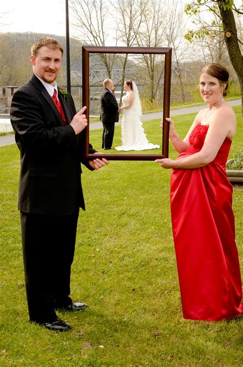 A Woman In A Red Dress Is Holding A Framed Photograph While A Man In A