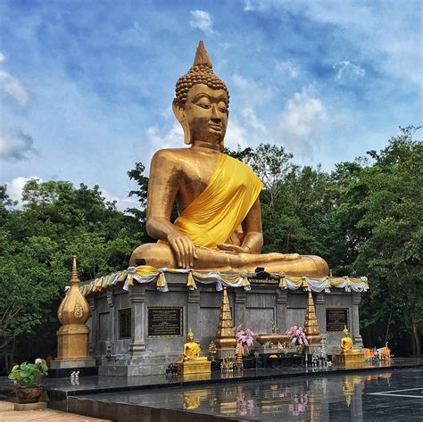 A Large Golden Buddha Statue Sitting On Top Of A Fountain