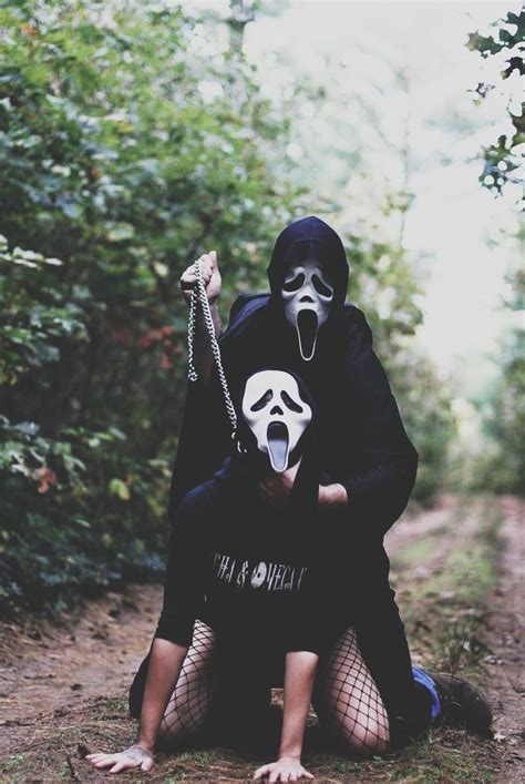 Two People With Masks On Their Faces Sit In The Woods And Pose For A Photo