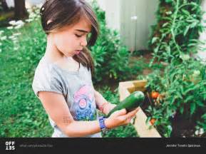 A Girl Holds A Cucumber From A Garden In Her Yard Stock Photo OFFSET