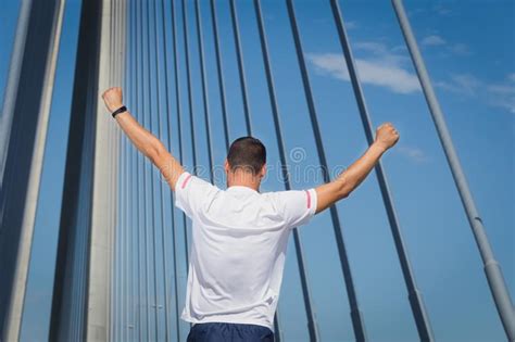 Athletic Man Runner Raised His Arms Up Standing On Bridge Stock Photo