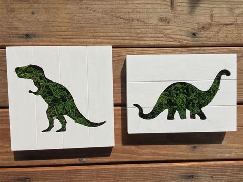 two coasters decorated with green dinosaur silhouettes on wood planks
