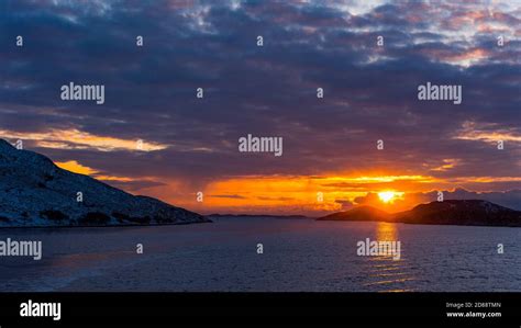 Glorious Sunset Over Norwegian Coast With Snow Covered Rocks And Dense