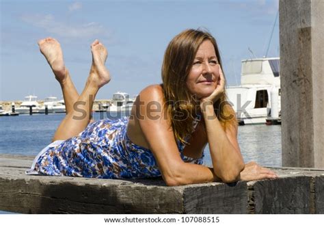 Sexy Mature Woman Enjoying A Relaxed Sunny Day Out At A Marina With Boats As Background