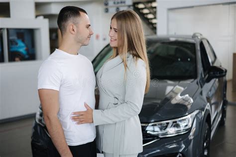 Portrait Of Beautiful Young Couple Happy After Buying New Car From Car Showroom Woman Hug Her