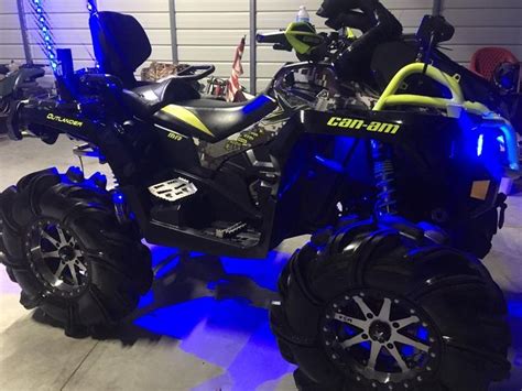 A Black And Yellow Atv Is Parked In A Garage With Blue Lights On The Tires