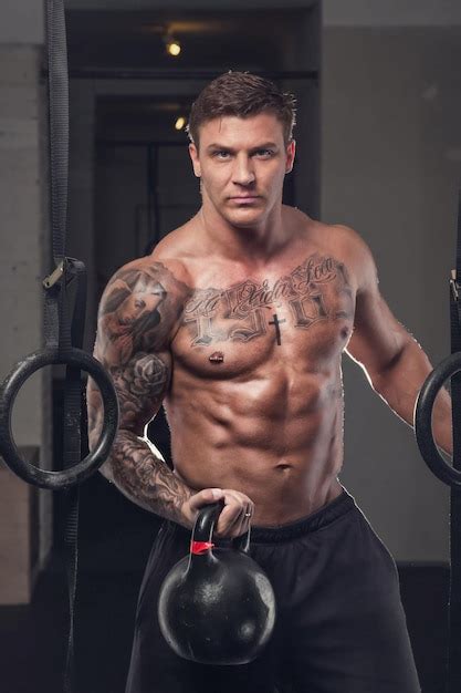 Premium Photo Tattooed Shirtless Man Holds Lifting Weight In A Gym Club