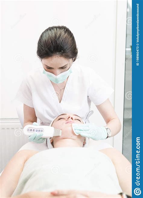 The Female Cosmetologist Makes A Procedure Of Ultrasonic Cleaning Face