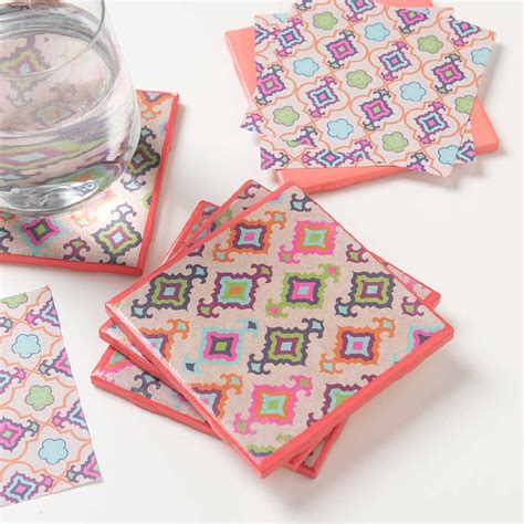 Four Square Coasters With Colorful Designs On Them Next To A Glass And