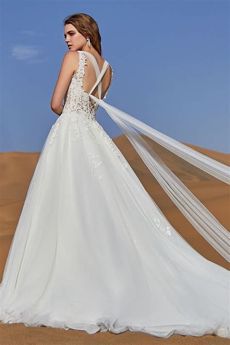A Woman In A Wedding Dress Standing On Top Of A Sand Dune With Her Back
