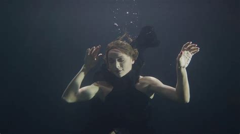 Beautiful Woman In Black Dress Swimming Underwater In Pool On Dark