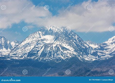 Snow Capped Peaks Of Rocky Mountains With Blue Sky And Clouds Stock