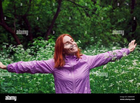 Happy Redhead Woman With Spread Hands Standing In A Forest With Closed