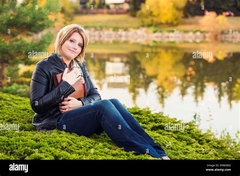 Mature Christian Woman Embracing Her Bible In A Park Beside A Lake In Autumn Edmonton Alberta