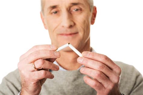 Close Up Of Man Breaking Cigarette Against White Background Stock Photo