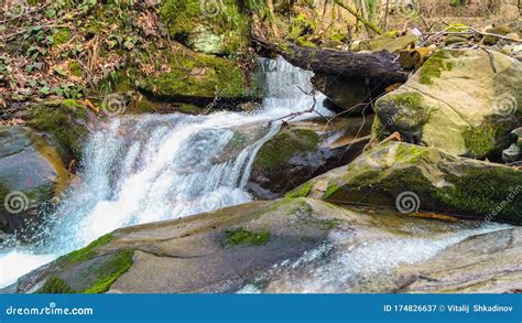 The Water Of A Mountain Stream Flows Among Large Stones Covered With