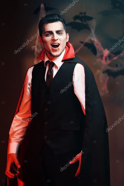 Young Man Dressed As Vampire For Halloween Party On Dark Background
