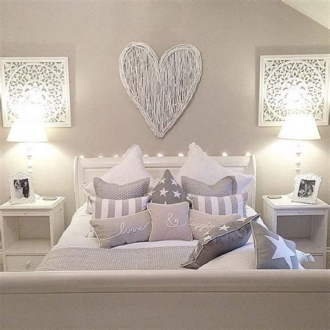 A White Bed Topped With Lots Of Pillows Next To Two Nightstands Filled