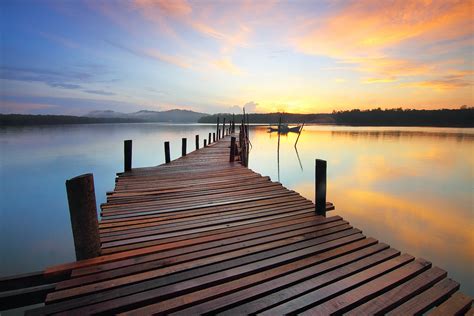 Brown Wooden Dock On Calm Body Of Water Surrounded By Silhouette Of