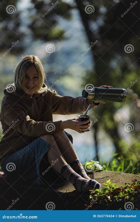 A Woman In The Park In Pouring Hot Water From A Thermos Into A Mate Cup