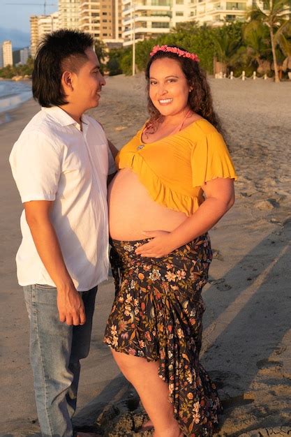 retrato de embarazada mujer latina y ella marido se abrazar en la playa foto premium