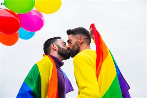 Joven pareja gay besándose en un desfile Foto Gratis