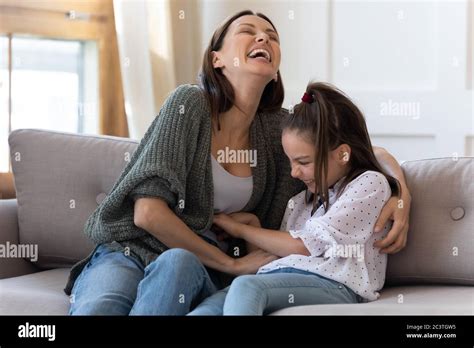 Happy Mother Tickling Adorable Daughter Playing Funny Game At Home