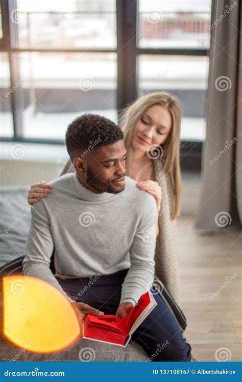 Happy Interracial Couple Spending Weekend Together At Home Relaxing With Book Stock Image