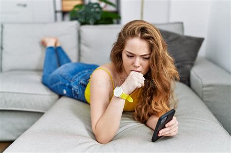 Young Caucasian Woman Lying On The Sofa Using Smartphone Feeling Unwell