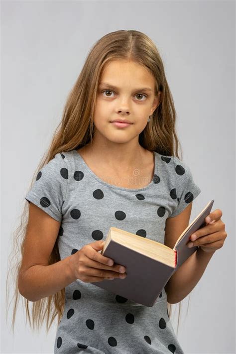 A Menina Bonita Da Criança De Dez Anos Lê Um Livro E Olhares No Quadro