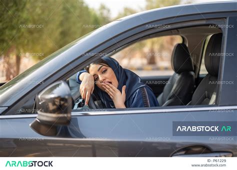 امرأه عربية خليجية سعودية محجبة تجلس في السيارة وتضع يدها على فمها وتتثاءب،ايماءات وجه ويدين تدل