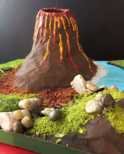 A Cake Made To Look Like A Volcano With Rocks And Grass On Its Sides