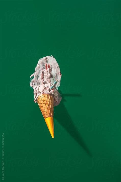 An Ice Cream Cone With Pink And White Toppings On Green Background By