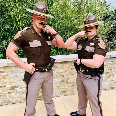 Two Police Officers Standing Next To Each Other With Fake Mustaches On