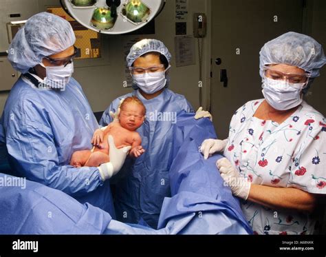 A Doctor And Nurse In A Hospital Delivery Room With A Newborn Infant