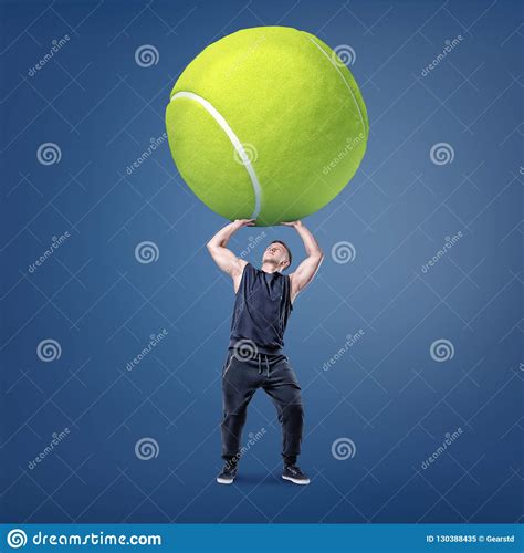 A Small Young Muscular Man Tries To Hold A Giant Yellow