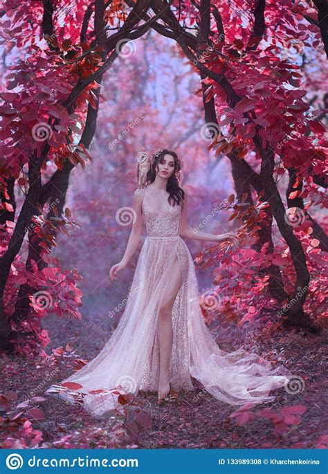 mysterious attractive lady in a long light luxury dress in a magical pink forest gate to the