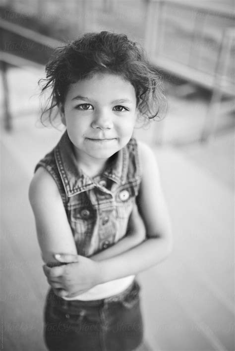 Black And White Portrait Of A Confident Young Girl With Folded Arms Looking At Camera By