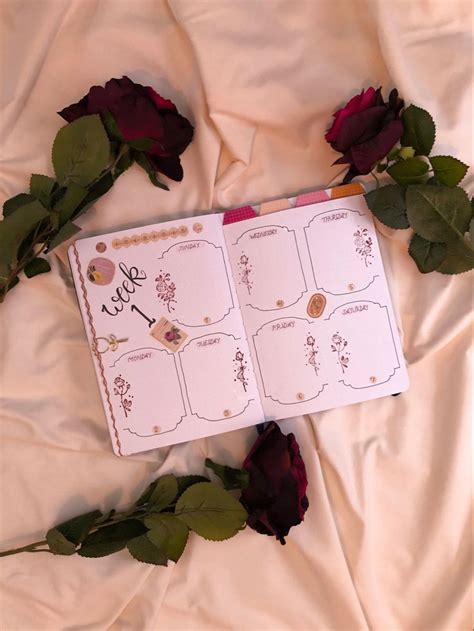 An Open Planner Sitting On Top Of A Bed Next To Roses